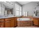 Bathroom with double vanity, large tub with tile surround, and shuttered window for natural light at 675 Greenford N Trl, Carmel, IN 46032