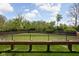 Scenic community pond featuring a black metal fence, concrete surround, and lush green landscaping at 675 Greenford N Trl, Carmel, IN 46032