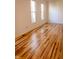 Bright empty room featuring hardwood floors and two windows, creating a warm and inviting space at 6967 Bluffridge Way, Indianapolis, IN 46278