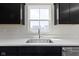 Close up of kitchen sink and countertop with black cabinets and a window view at 7167 Finley Creek Dr, Whitestown, IN 46075