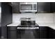 Stainless steel stove and microwave surrounded by black cabinets and white countertops at 7167 Finley Creek Dr, Whitestown, IN 46075