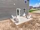 Backyard view of the patio with a set of four white Adirondack chairs and side tables at 7167 Finley Creek Dr, Whitestown, IN 46075