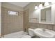 This bathroom features tile flooring and walls, a toilet, and a sink with a mirror at 8553 Broadway St, Indianapolis, IN 46240