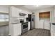 Well-lit kitchen featuring stainless steel appliances, white cabinets, and vinyl flooring at 8553 Broadway St, Indianapolis, IN 46240