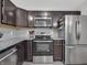 Modern kitchen with stainless steel appliances, granite countertops, dark cabinetry and a tile backsplash at 10844 Tedder Lake Dr, Indianapolis, IN 46239