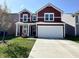 Charming two-story home featuring red siding, white trim, a two-car garage, and a well-manicured lawn at 1380 Delacorte Cir, Shelbyville, IN 46176