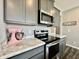 Well-equipped kitchen with stainless steel appliances, marble countertops, and gray cabinetry at 1380 Delacorte Cir, Shelbyville, IN 46176