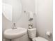 Modern half bathroom with a pedestal sink, round mirror, and toilet at 2023 Alvord St, Indianapolis, IN 46202