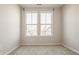 Bright, empty room with neutral carpet, two large windows, and a view of the neighboring homes at 2023 Alvord St, Indianapolis, IN 46202