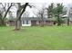 View of backyard featuring brick house with porch and ample greenery at 2302 W 61St St, Indianapolis, IN 46228