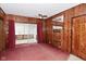 Living room with vintage wood paneling, plush carpeting, and sliding glass doors at 2302 W 61St St, Indianapolis, IN 46228