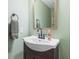 Well-lit powder room with a pedestal sink, decorative mirror, and neutral green walls at 3130 Shadow Lake Dr, Indianapolis, IN 46217
