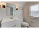 This bathroom boasts a bright vanity with modern sconces, complemented by a neutral color scheme and white fixtures at 334 N 15Th Ave, Beech Grove, IN 46107