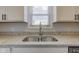 Close-up of a stainless-steel kitchen sink with granite countertops and white cabinets at 334 N 15Th Ave, Beech Grove, IN 46107