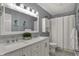 Bathroom with double sink, shower, white vanity, framed mirror, and accent art at 5223 Jerry Ct, Indianapolis, IN 46254
