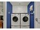 Laundry room with blue walls featuring a washer, dryer and white storage cabinets at 5223 Jerry Ct, Indianapolis, IN 46254