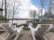 Inviting brick patio featuring two white Adirondack chairs overlooking a serene lake and private boat dock at 6599 Meadowlark Dr, Nineveh, IN 46164