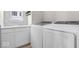 Well-lit laundry room featuring white cabinets, sink, and modern washer and dryer at 7012 Pickett Pl, Carmel, IN 46033