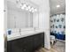 Bright bathroom featuring a double vanity and a shower with blue floral curtains at 7418 Bluebird Ct, Indianapolis, IN 46254