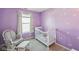 Charming Bedroom featuring a white crib, a cozy chair, a window, and daisy decals on the walls at 7418 Bluebird Ct, Indianapolis, IN 46254
