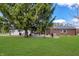 Expansive backyard with manicured lawn, mature shade tree, and a brick home with a patio; a great outdoor space at 7859 Jennifer Ln, Brownsburg, IN 46112