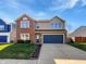 Two-story home featuring a two-car garage, brick accents, and a well-manicured lawn on a bright, sunny day at 8251 Garden Ridge Rd, Indianapolis, IN 46237