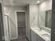 Bathroom with double sink vanity, white cabinets, large mirror and walk-in closet access at 10319 Pronghorn Ln, Indianapolis, IN 46239