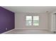 Spacious bedroom featuring two windows with blinds, a purple accent wall, neutral paint, and plush carpeting at 10319 Pronghorn Ln, Indianapolis, IN 46239