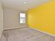 Bright bedroom featuring a yellow accent wall, a window with blinds, neutral paint, and plush carpeting at 10319 Pronghorn Ln, Indianapolis, IN 46239