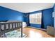 This bedroom offers hardwood floors, blue walls and a large window that allows for ample natural light at 10955 Balfour Dr, Noblesville, IN 46060