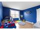 This well-lit bedroom features hardwood floors, blue walls, a window and ample space at 10955 Balfour Dr, Noblesville, IN 46060