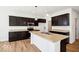 Modern kitchen featuring dark cabinetry, stainless steel appliances, a large island, and wood-look flooring at 1117 Stubble Run, Danville, IN 46122