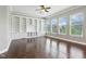 Bright living room with hardwood floors, a ceiling fan, a wall of built-in shelving and multiple windows at 13494 Moorcroft Dr, Fishers, IN 46037
