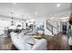 Open-concept living room with modern sofas, hardwood floors, staircase, and an open view into the kitchen at 16193 Burnt Rock Ln, Fortville, IN 46040