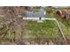 Aerial view of a home with a patio, a fenced yard with green grass, and mature trees at 1707 W 76Th Pl, Indianapolis, IN 46260
