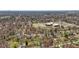Aerial view showcasing homes in a quiet neighborhood with mature trees, streets, and a school nearby at 1707 W 76Th Pl, Indianapolis, IN 46260
