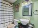 Small bathroom with green walls, decorative mirror, and shower with curtain at 1707 W 76Th Pl, Indianapolis, IN 46260