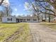 Charming single-story home featuring light blue siding, dark shutters, a fountain, and a paved driveway at 1707 W 76Th Pl, Indianapolis, IN 46260