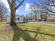 Inviting single-story home with light blue siding, black shutters, large trees, and a well-manicured lawn at 1707 W 76Th Pl, Indianapolis, IN 46260