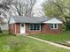 Charming brick home with green shutters, a well-manicured lawn, and a welcoming walkway at 2120 Sheffield Ave, Anderson, IN 46011