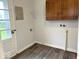 Functional laundry area featuring upper cabinets, shelving, and wood-look flooring at 2120 Sheffield Ave, Anderson, IN 46011