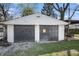 Two car detached garage with black doors, and partial view of patio with outdoor seating at 2221 Groff Ave, Indianapolis, IN 46222