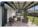 Covered outdoor patio with wicker seating and a brick floor, next to the detached garage at 2221 Groff Ave, Indianapolis, IN 46222