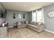 Cozy living room featuring gray walls, wood floors, a gray sectional sofa, and large windows with curtains at 2960 W Patchwork Dr, Monrovia, IN 46157