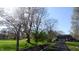 A long driveway leads to a charming two-story brick home with an attached garage, framed by trees and a green lawn at 3790 E Pleasant Run Parkway North Dr, Indianapolis, IN 46201