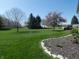 Expansive backyard with lush green grass, mature trees, and an inviting deck area for outdoor enjoyment at 4309 Summerhaven Dr, New Palestine, IN 46163