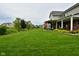 Large backyard featuring a pergola, covered porch, patio seating, and meticulously maintained landscaping at 4415 Voyageur Way, Carmel, IN 46074