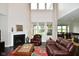 Bright living room with tall windows, fireplace, leather furniture, and an open floor plan at 4415 Voyageur Way, Carmel, IN 46074