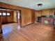 Hardwood floor living room features a brick fireplace, paneled walls, ceiling light, and doorway to an adjoined room at 505 W 40Th St, Indianapolis, IN 46208