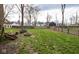Backyard area showcasing green grass, mature trees, outdoor seating, and a cozy fire pit at 5654 Broadway St, Indianapolis, IN 46220